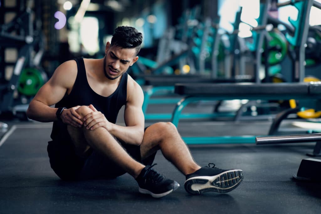 homem com lesão no joelho na academia crossfit lesiona