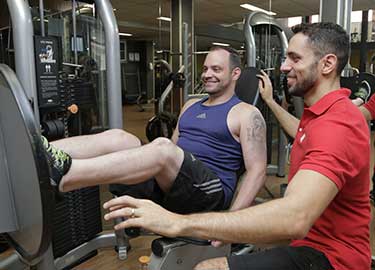 personal trainer e aluno no leg press