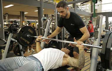 personal trainer e aluno fazendo supino musculação