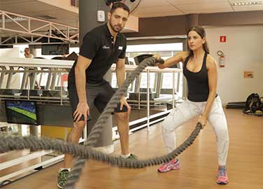 personal trainer e aluna com corda naval