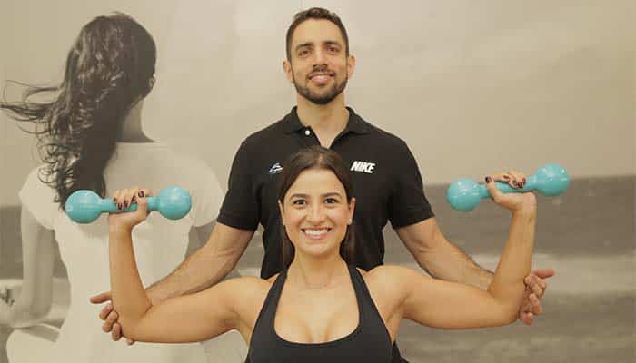 Rafael Figueiredo personal trainer em Alphaville e aluna exercício desenvolvimento