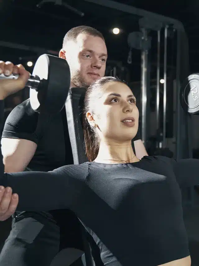 mulher treinando musculação com personal trainer- desenvolvimento de ombros