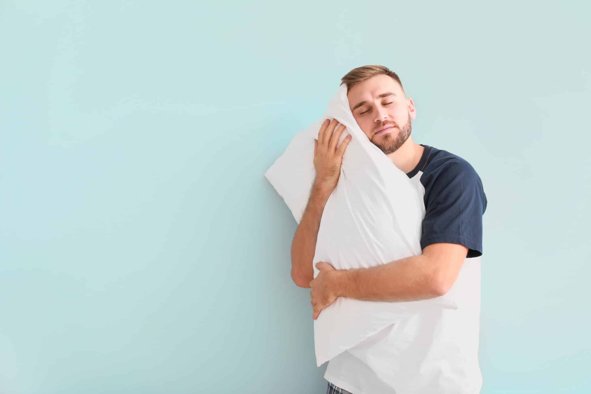 A importância do descanso para os resultados no treino Sleepy young man with pillow on light background