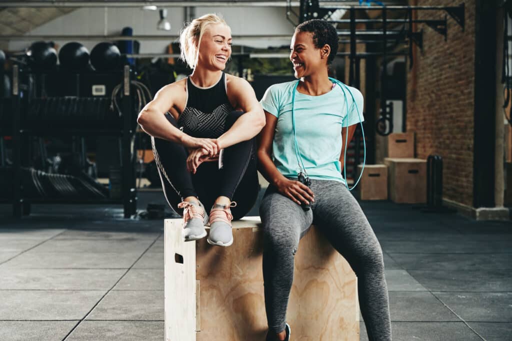 Fit young female friends laughing together after a gym workout